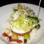 Goat cheese soup being poured over bacon, lardo, tofu, green apple and frisée salad