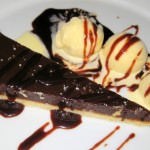 Chocolate caramel tart with bitters and orange ice cream and Nocino chocolate sauce